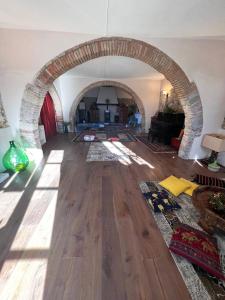 een woonkamer met een boog in een kamer met houten vloeren bij Casale Saundarya - yoga e ayurveda in Toscana in Casciana Terme