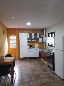 una cocina con armarios blancos, una mesa, una mesa y un tocador en Borde Rio Coyhaique Cabaña y Tinaja, en Coyhaique