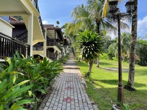 a walkway in front of a house with palm trees at 101 Resort & Spa, Janda Baik in Kampong Sum Sum