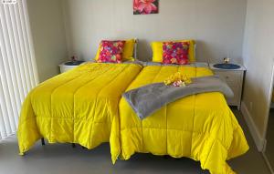 a bedroom with a yellow bed with a yellow comforter at The Art Garden- Hibiscus Guesthouse in Hawaiian Ocean View