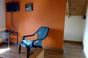 einem grünen Stuhl in einem Zimmer mit orangefarbener Wand in der Unterkunft La casa de chocolate 1 in Bogotá
