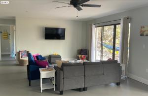 sala de estar con sofá y TV en The Art Garden- Hibiscus Guesthouse, en Hawaiian Ocean View
