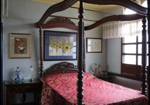 a bedroom with a canopy bed with a pink bedspread at CASA CONCHITA BED & BREAKFAST in Taal