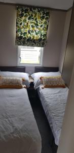 two beds in a small room with a window at Warner Lane in Selsey