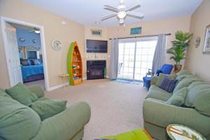 a living room with a green couch and a surfboard at Sea Bright 205 condo in Ocean City