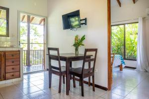 a dining room with a table and chairs and a tv at Villas en el Bosque in Ojochal