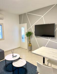 Rambam BEACH apartment في حيفا: غرفة مع طاولة وكرسيين وتلفزيون