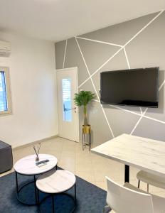 een kamer met een tafel en twee stoelen en een televisie bij Rambam BEACH apartment in Haifa