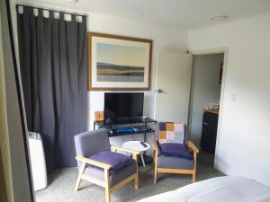 um quarto com duas cadeiras, uma secretária e uma televisão em A little bit of country on the city's doorstep em Napier