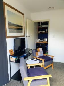 a living room with a tv and two chairs at A little bit of country on the city's doorstep in Napier