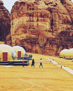 a group of people walking in front of a mountain at Toleen Camp wadi rum in Wadi Rum