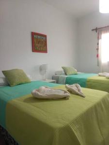 Habitación con 3 camas con sábanas verdes. en Amplia casa para 6 huéspedes en Mendoza en Godoy Cruz
