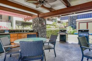un patio avec une table, des chaises et un grill dans l'établissement Paradise Found at White Sands Village 105, à Kailua-Kona