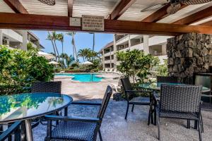 un patio con mesas y sillas y una piscina en Paradise Found at White Sands Village 105 en Kailua-Kona
