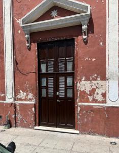 un edificio rojo con una puerta de madera. en Departamento Barrio de Santiago en Mérida