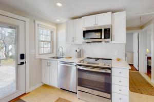 a kitchen with white cabinets and a stove top oven at Adventures on Buzzards Bay in Bourne