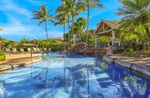 einen Pool in einem Resort mit Palmen in der Unterkunft Nihilani 31A in Princeville