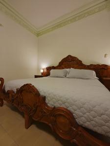 a large wooden bed in a white bedroom at Hotel Gran Domo in León