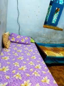 a bedroom with a purple bed with flowers on it at البيت النوبي in Naj‘ al Maḩaţţah