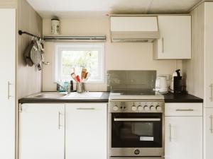a kitchen with white cabinets and a sink and a stove at Cozy chalet for 5p with garden in a lovely area near Goedereede in Goedereede