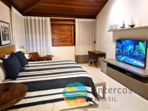 a bedroom with a bed and a flat screen tv at Villa Biarritz, Praia do Forte in Praia do Forte