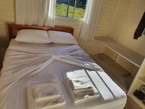uma cama num pequeno quarto com uma janela em Casa p fim de semana p 6 pessoas 12km, do centro de urupema em Urupema