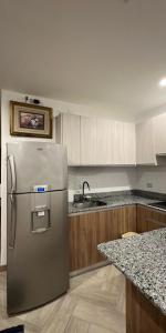 een keuken met een roestvrijstalen koelkast en houten kasten bij Apartamento Violeta con Impresionante Vista al Mar in Playas