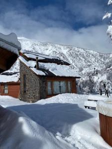 een huis bedekt met sneeuw met een berg op de achtergrond bij Cabañas Alto Cordillera in Las Trancas