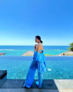 Una mujer con un vestido azul de pie junto al océano en Cliff front luxury Olala Nusadua Beach, en Nusa Dua