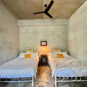 two beds in a room with a ceiling fan at MIRAMONTI House 賣房間更賣生活 in Xikou