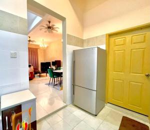 a kitchen with a refrigerator and a yellow door at Homestay D Razak Wakaf Tapai in Marang
