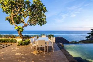 a dining room with a table and chairs and the ocean at Cliff front luxury Olala Nusadua Beach in Nusa Dua
