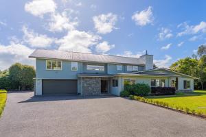 a blue house with a driveway at Anam Cara Gardens luxury Villa in Otaki