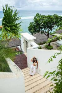una mujer está de pie en una escalera cerca del océano en Cliff front luxury Olala Nusadua Beach en Nusa Dua