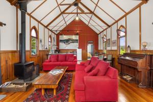 ein Wohnzimmer mit roten Sofas und einem Klavier in der Unterkunft The Chapel- Kohukohu in Kohukohu Town District