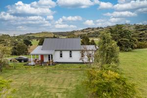 a white house in the middle of a field at The Chapel- Kohukohu in Kohukohu Town District