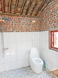 a bathroom with a toilet in a brick wall at Du Già Coffee View Homestay in Làng Cac