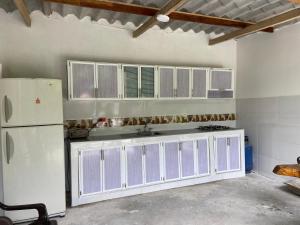 La cuisine est équipée de placards blancs et d'un réfrigérateur blanc. dans l'établissement Hostal y Camping Villa Guadua Tayrona, à Santa Marta