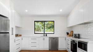 a white kitchen with white cabinets and a window at Glen View in Johanna