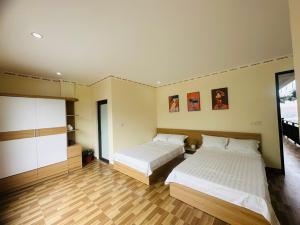 um quarto de hotel com duas camas e pisos de madeira em Sơn Trang House em Sapa