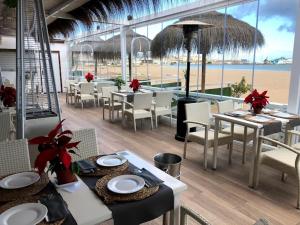 un restaurante con mesas y sillas y vistas a la playa en ApartPlaya (1ª Línea) en Melilla