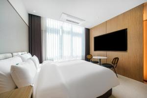 a bedroom with a large white bed and a tv at H-Avenue Hotel Geomdan New Town in Incheon