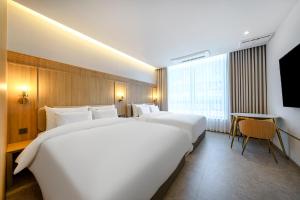a hotel room with two beds and a flat screen tv at H-Avenue Hotel Geomdan New Town in Incheon