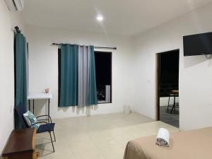 een kamer met een bed, een tv en 2 ramen bij Hotel Miriam Bacalar in Bacalar