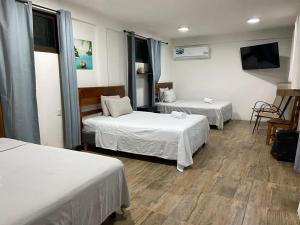 a hotel room with two beds and a flat screen tv at Hotel Miriam Bacalar in Bacalar