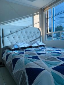 um quarto com uma cama com um edredão azul e branco em Habitación Queen em Bogotá