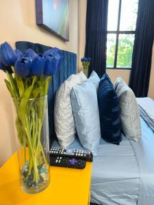 a vase of blue flowers on a table with a remote control at Luxury Midtown Flats near Downtown Memphis & FedEx Forum in Memphis