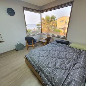 a bedroom with a large bed and a large window at Sea and Noeul Healing House in Seogwipo