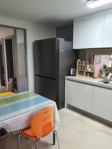 a kitchen with a table and a black refrigerator at Sea and Noeul Healing House in Seogwipo