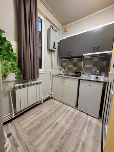a kitchen with white cabinets and a wooden floor at Мини дом целиком около мед центра Астхик in Yerevan